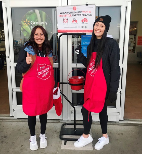 Two female NIC students ringing the bell for the salvation army